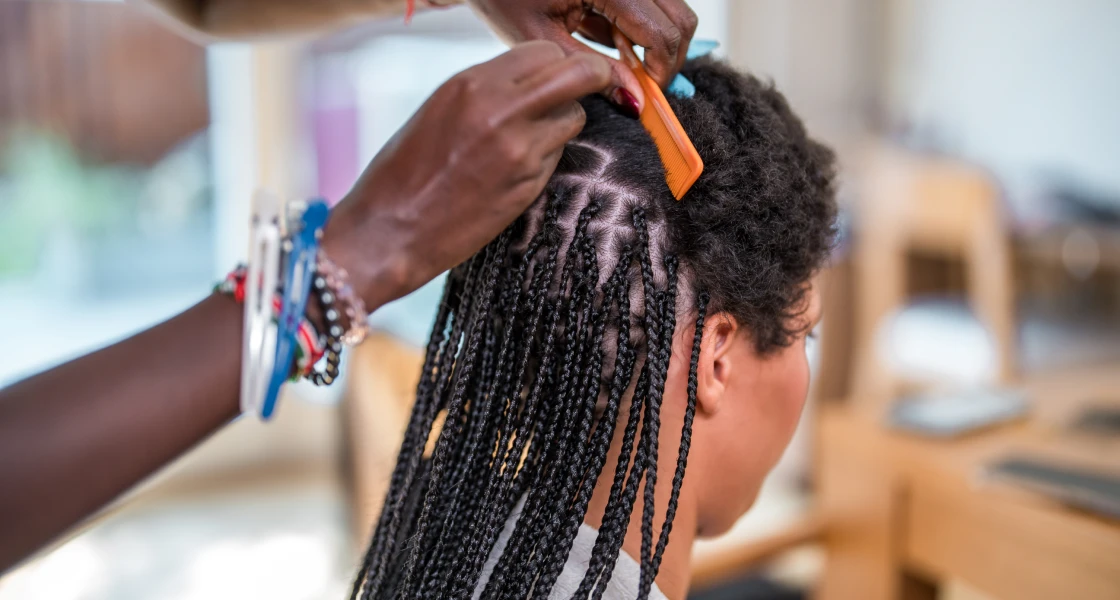 Woman getting her hair done at a salon, with a person holding a pair of scissors