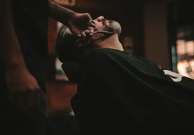 Barber performing a close shave on a client in a barbershop