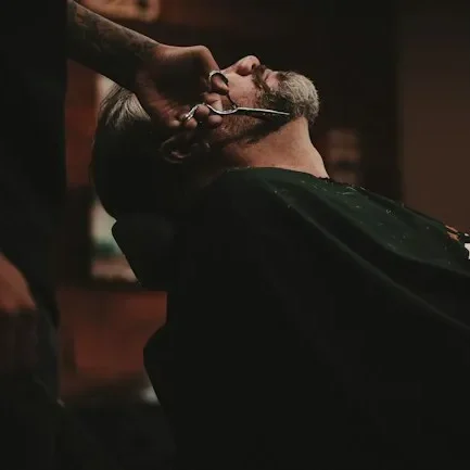 Barber performing a close shave on a client in a barbershop