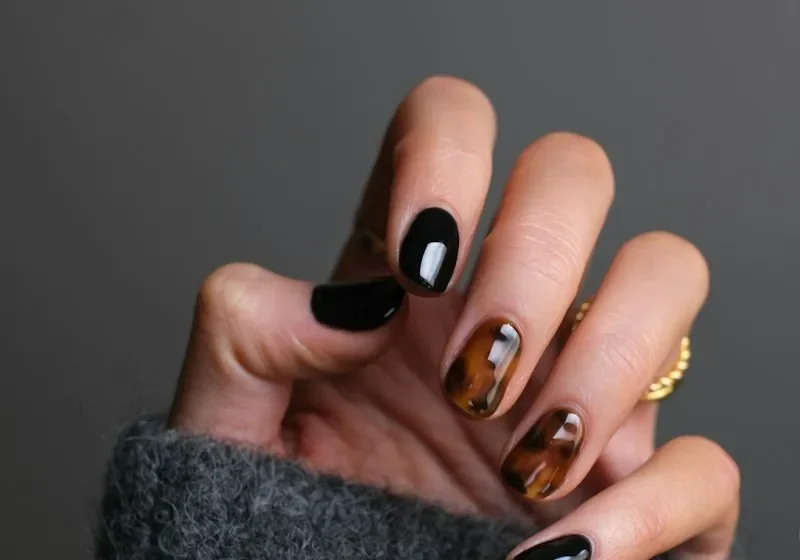 Hand with black nail polish against a neutral background