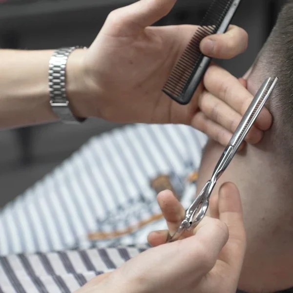 Man getting his hair cut by a barber, with the barber holding a pair of scissors